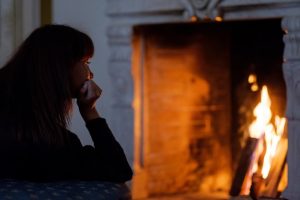 portrait-attractive-woman-looking-fire-daydreaming-front-fireplace_